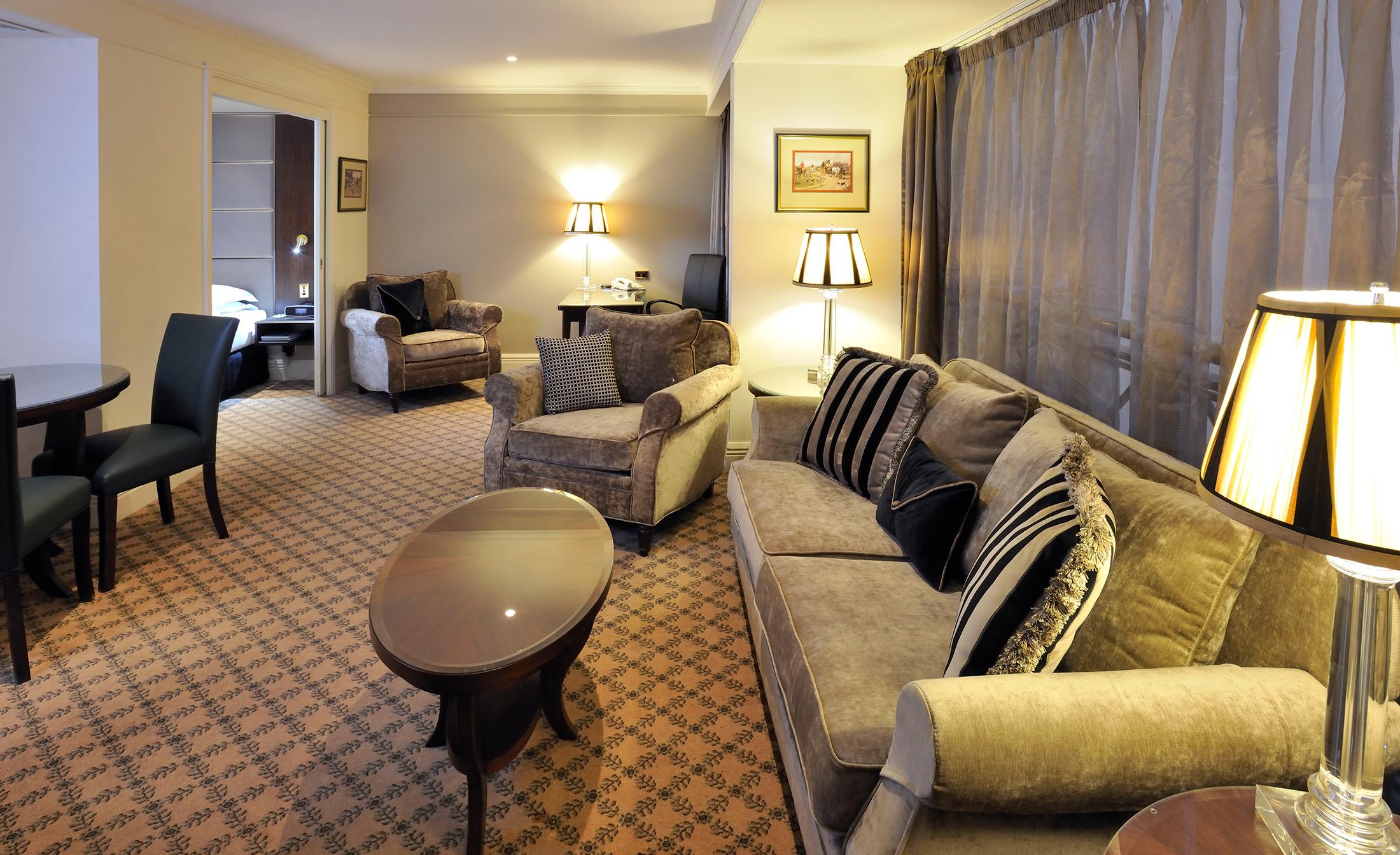Hotel Stamford Plaza Melbourne Esterno foto The photo shows a stylish and comfortable living area. It features plush seating, including a sofa with decorative cushions and a couple of armchairs. There's a circular coffee table in the center of the seating arrangement. The room has soft lightin