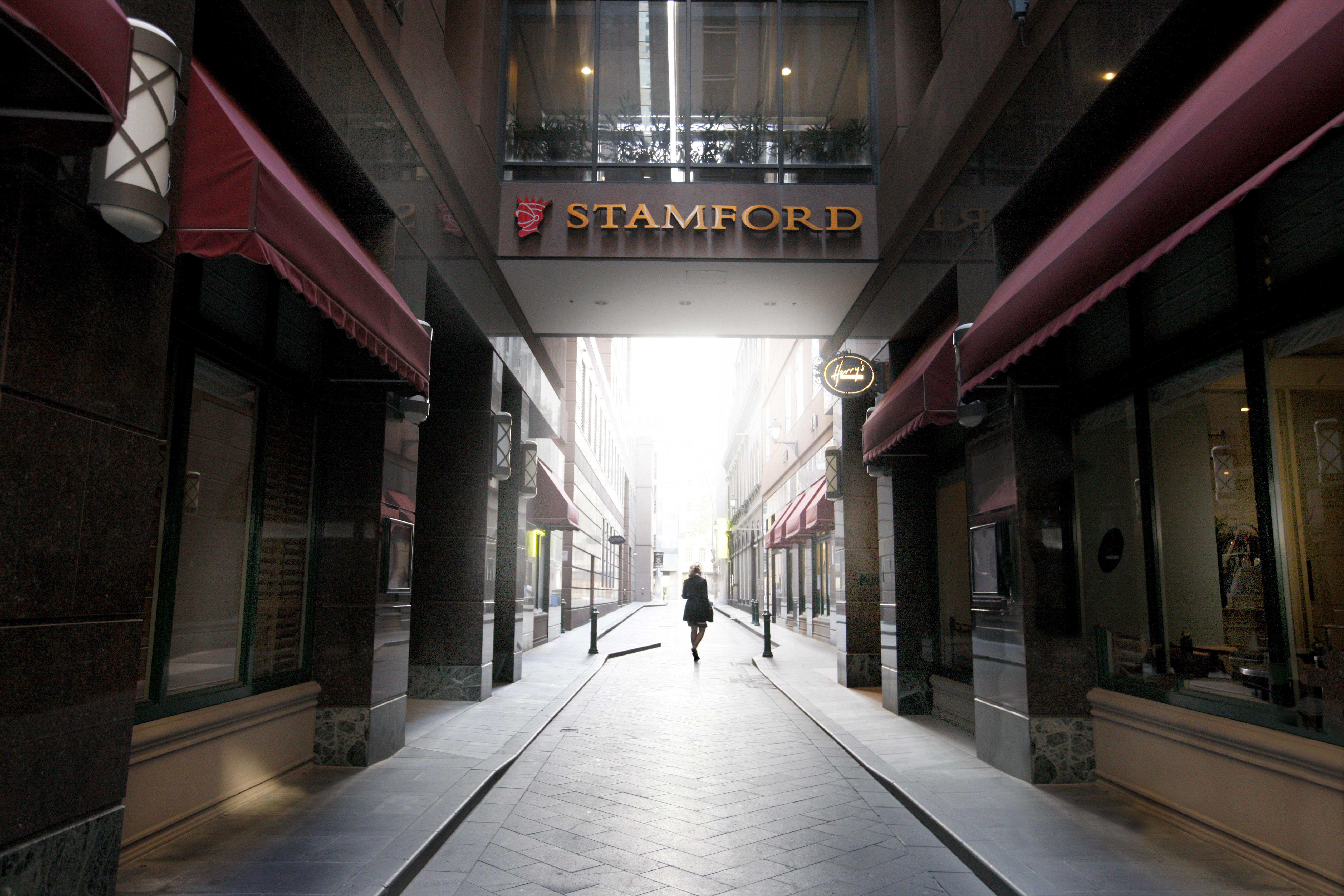 Hotel Stamford Plaza Melbourne Esterno foto The photo depicts a narrow alley or passageway, possibly in an urban setting. On one side, there are storefronts with canopies, and on the opposite side, there is a prominent sign reading "STAMFORD." The pathway is lined with buildings, creating a se
