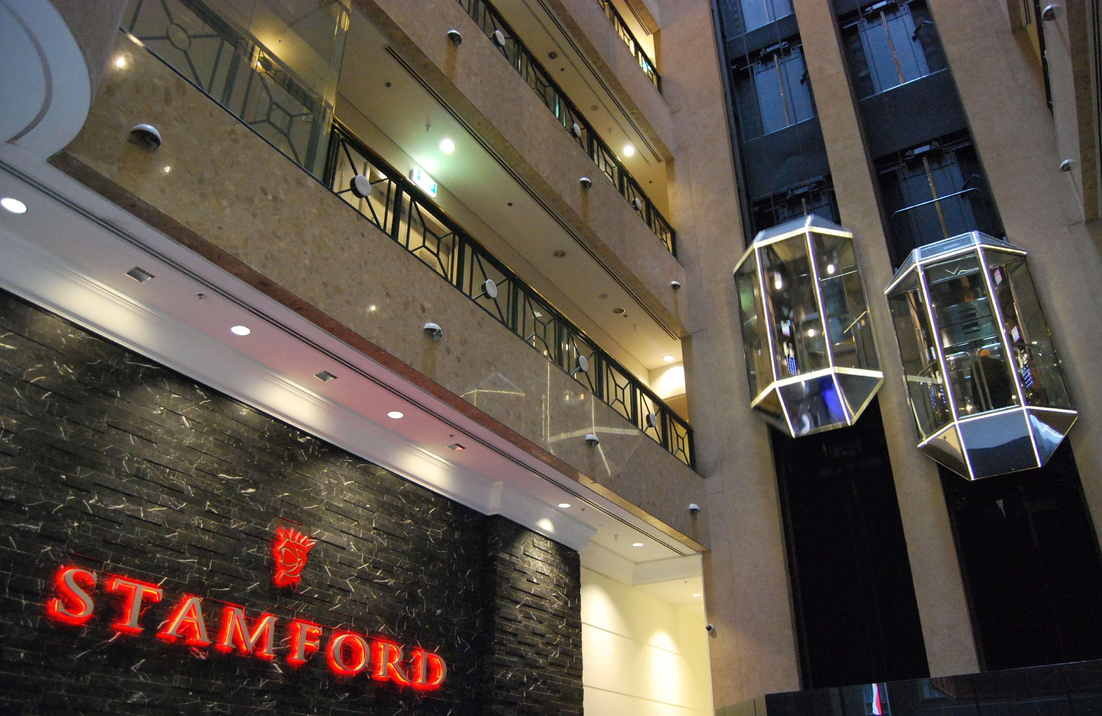 Hotel Stamford Plaza Melbourne Esterno foto The photo shows the interior of a building, likely a hotel or commercial space. There is a prominent sign with the name "STAMFORD" in red lettering against a dark stone background. The building features several floors, visible from the photograph, wi