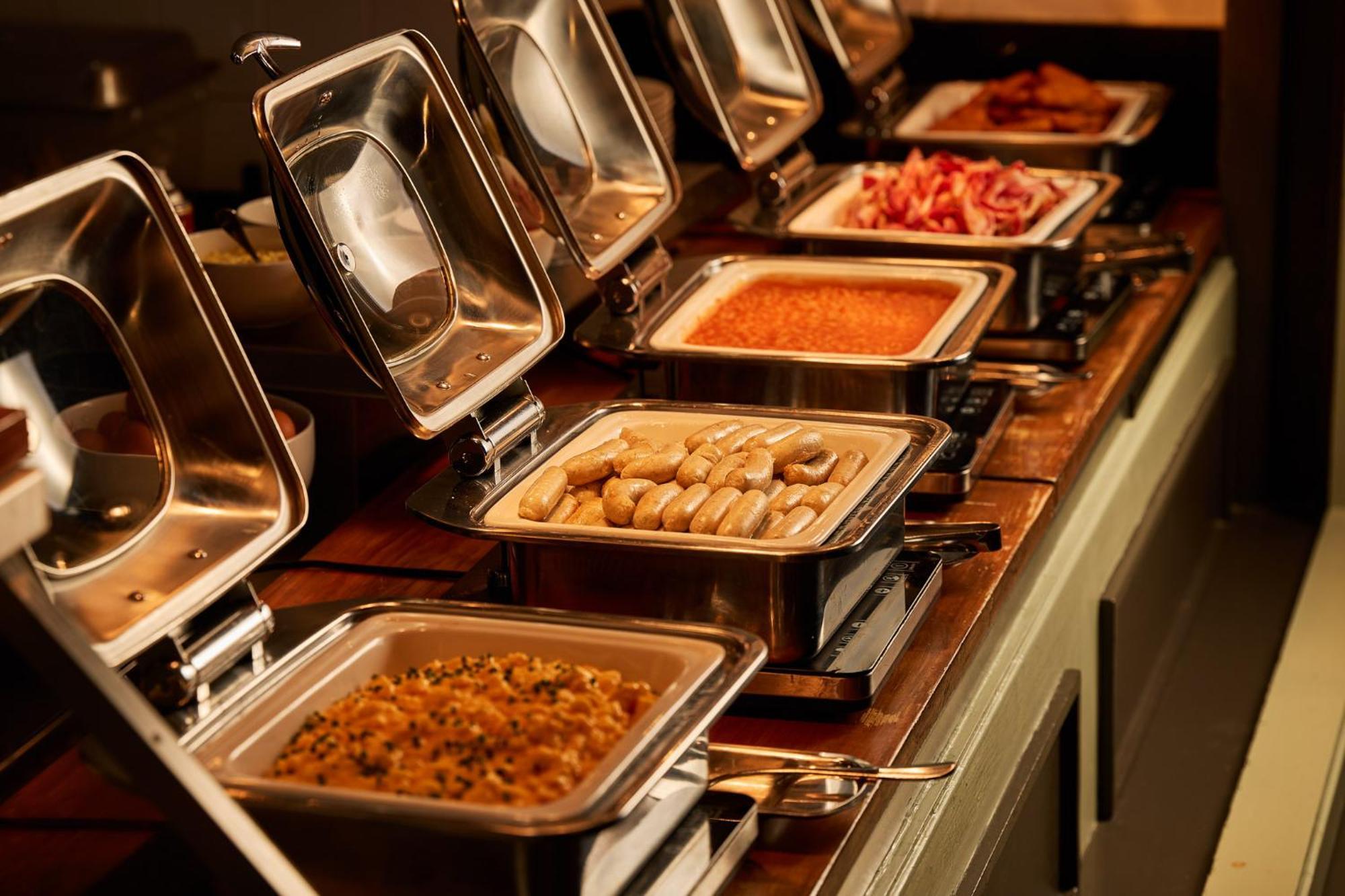 Hotel Stamford Plaza Melbourne Esterno foto The photo depicts a buffet setup featuring multiple food trays in stainless steel chafing dishes. Each dish is opened to display different types of food. The dishes contain a variety of items, which might include a mix of proteins, vegetables, or sta