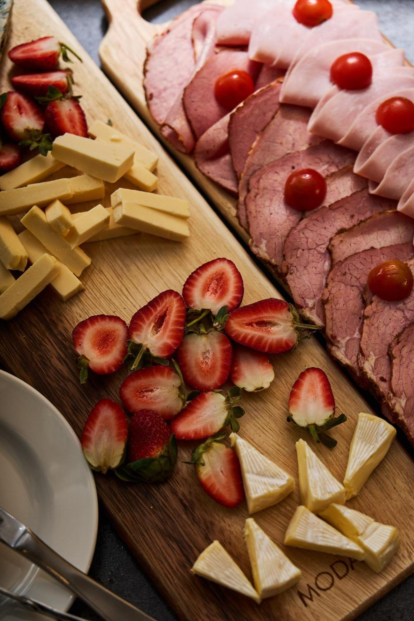 Hotel Stamford Plaza Melbourne Esterno foto The photo displays an assortment of food items arranged on a wooden surface. There are slices of various meats, including ham, alongside round cherry tomatoes. Next to the meat, there are several pieces of yellow cheese cut into sticks. Additionally,