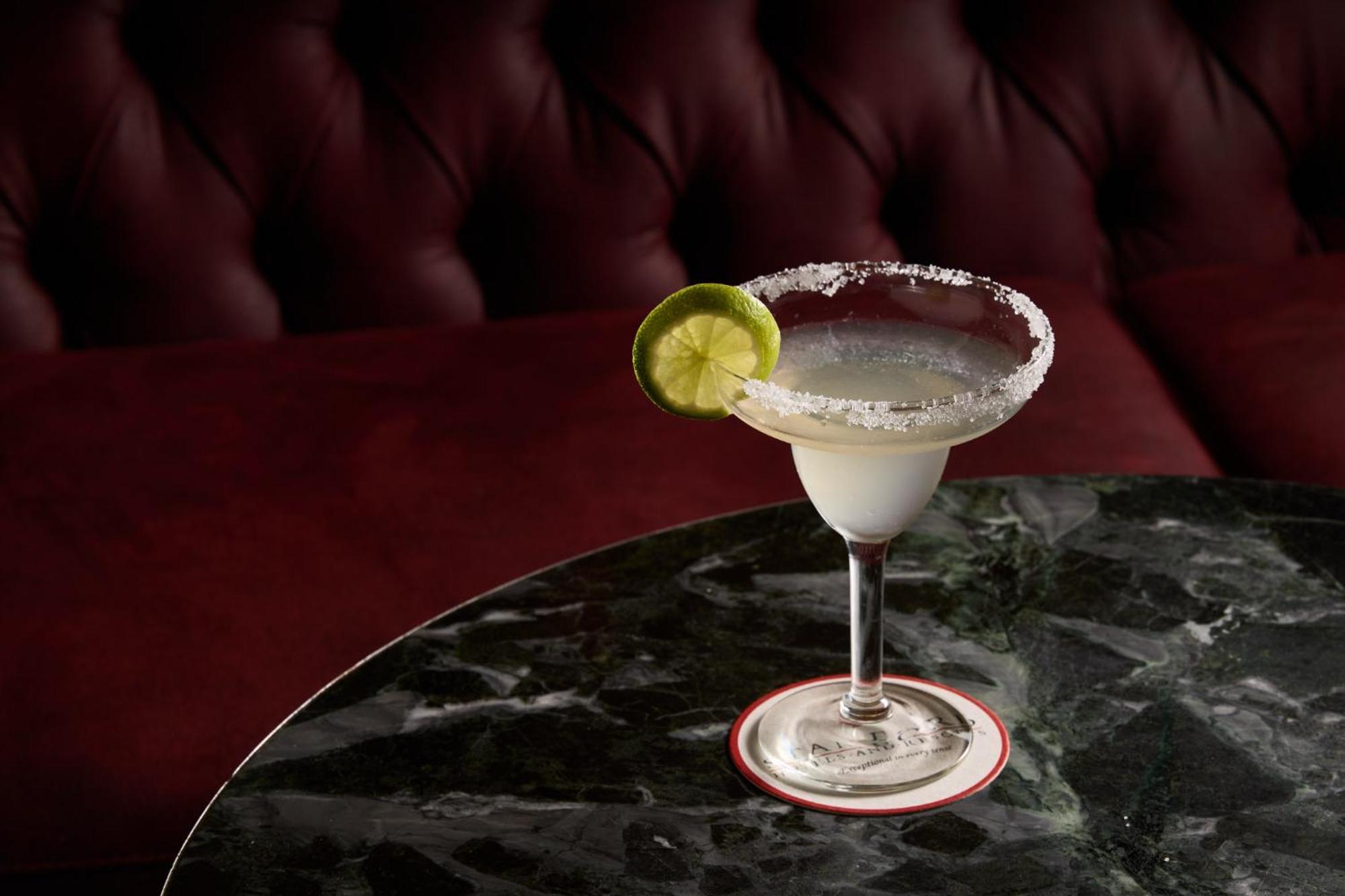 Hotel Stamford Plaza Melbourne Esterno foto The photo shows a beautifully presented margarita cocktail served in a classic margarita glass. The drink is clear with a salt rim around the edge, and adorned with a slice of lime. The glass is placed on a dark green marble table, contrasting with a