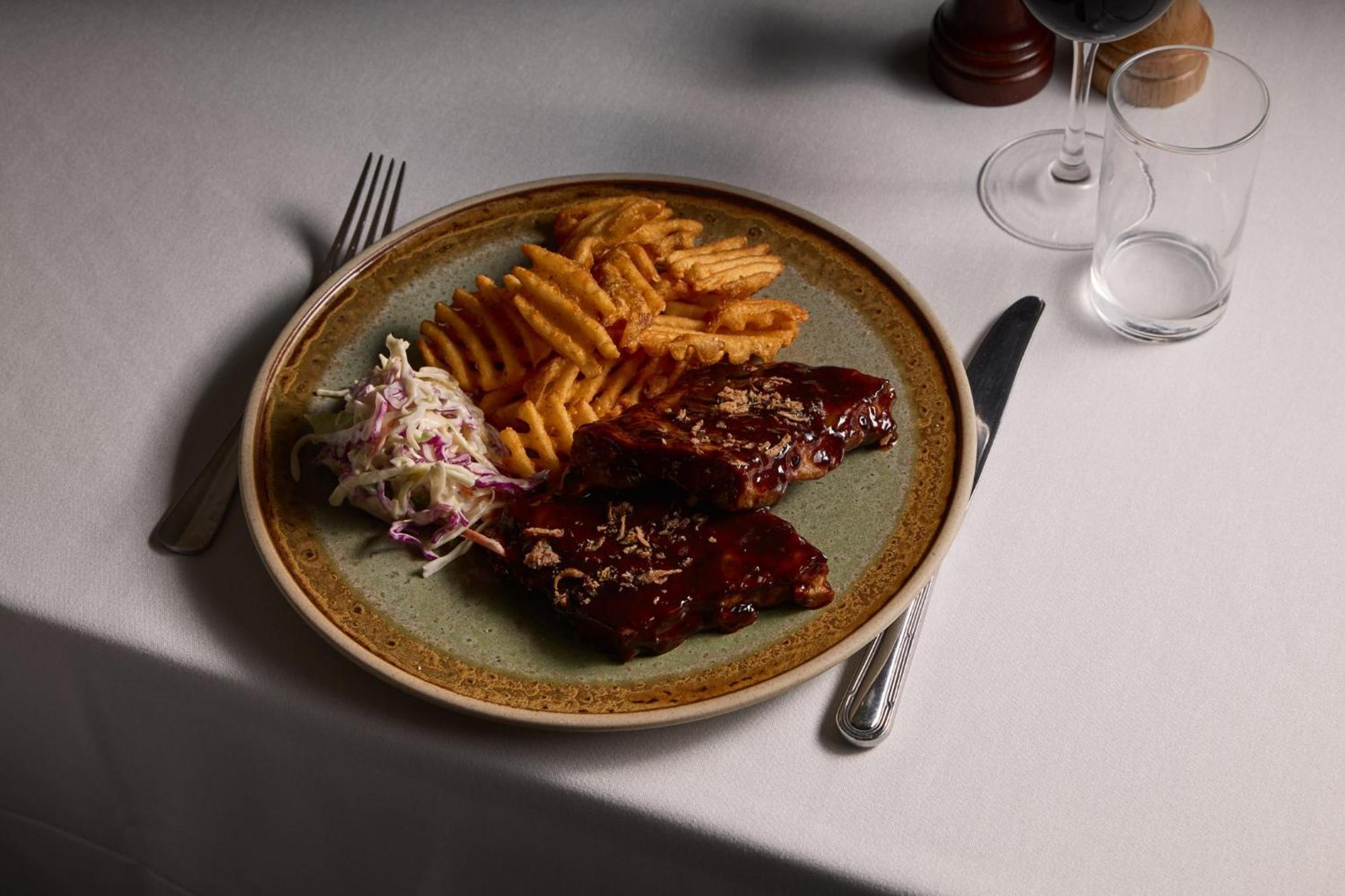 Hotel Stamford Plaza Melbourne Esterno foto The photo displays a plate of food featuring two pieces of steak that appear to be glazed with a rich sauce. Alongside the steak, there are crinkle-cut fries arranged neatly on one side of the plate. Additionally, there's a small serving of coleslaw,