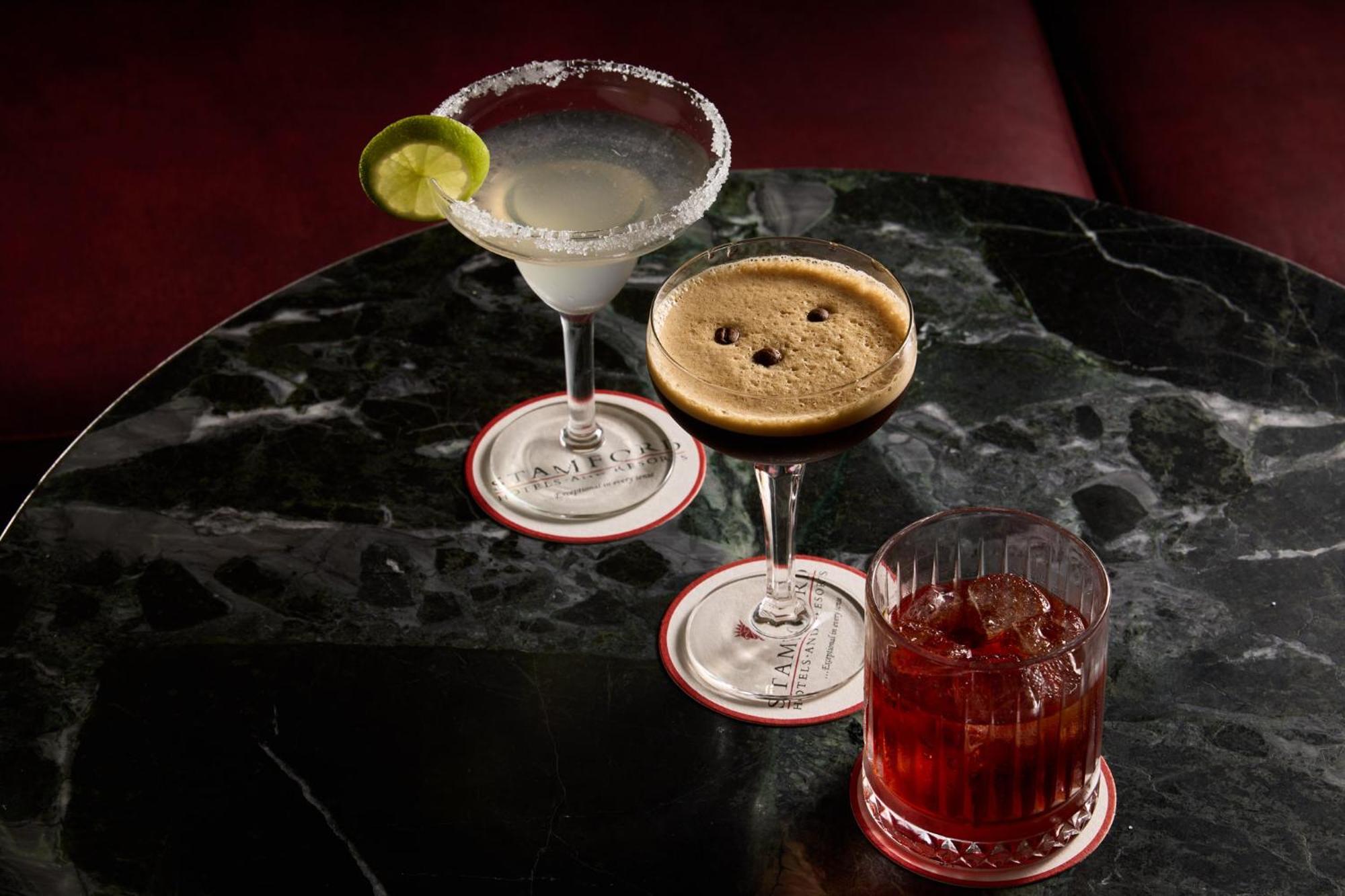 Hotel Stamford Plaza Melbourne Esterno foto The photo features three different cocktails displayed on a dark, marble table. 

1. **Left Cocktail**: A margarita served in a traditional glass, garnished with a lime wedge and featuring a salted rim.
2. **Middle Cocktail**: An espresso martini in 
