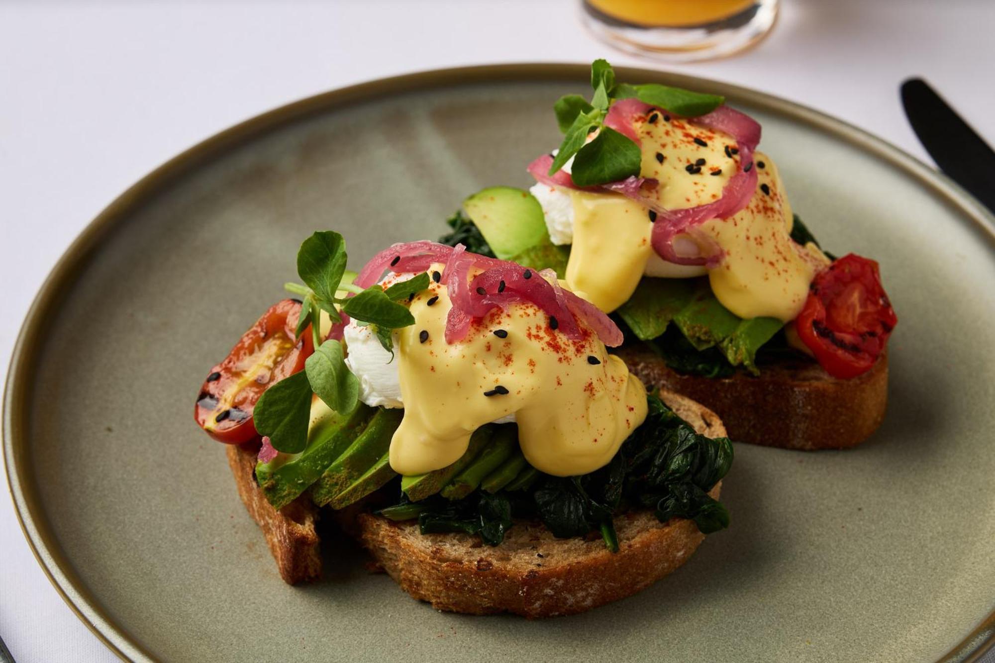 Hotel Stamford Plaza Melbourne Esterno foto The photo shows a plate featuring two pieces of toasted bread topped with a variety of ingredients. Each slice is layered with sautéed spinach and other greens, along with slices of cucumber and cherry tomatoes. The dish is finished with poached eggs