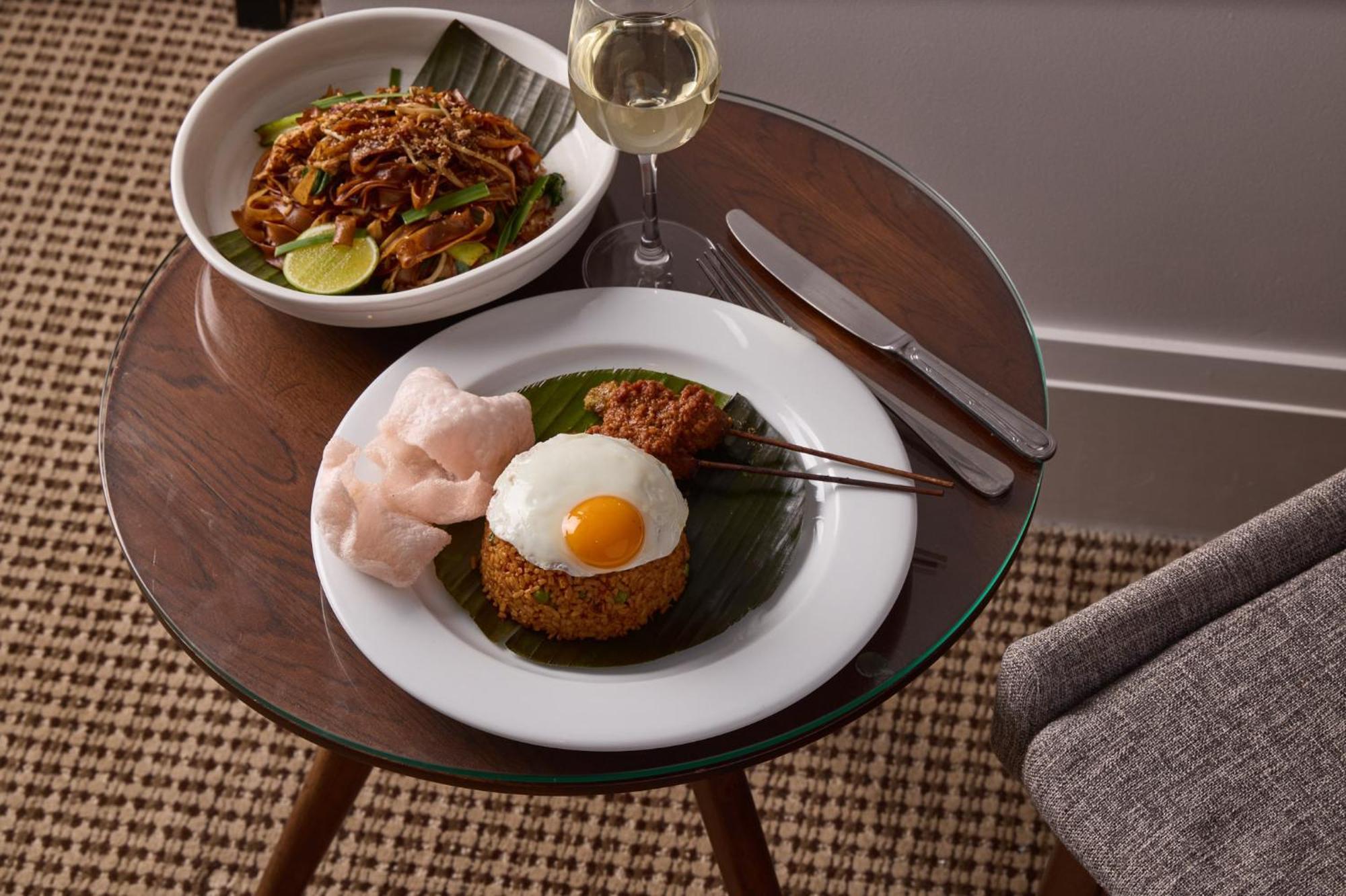 Hotel Stamford Plaza Melbourne Esterno foto The photo shows a beautifully arranged meal on a wooden side table. On a white plate, there is a serving of fried rice, topped with a sunny-side-up egg, accompanied by prawn crackers. The dish also features a small portion of what appears to be a spi