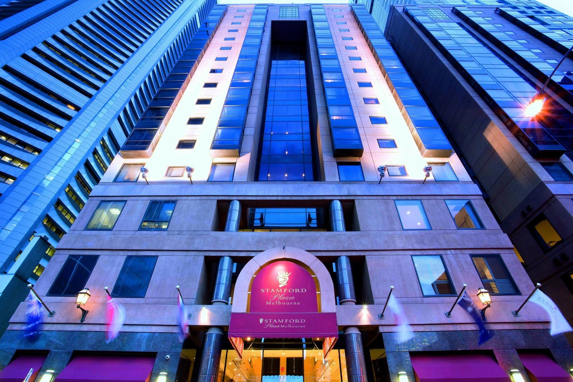 Hotel Stamford Plaza Melbourne Esterno foto The photo shows the exterior of a hotel, likely a luxury or high-end establishment. The building features a modern architectural design with a combination of glass and stone. The entrance is marked by a prominent sign, and the facade is illuminated, 